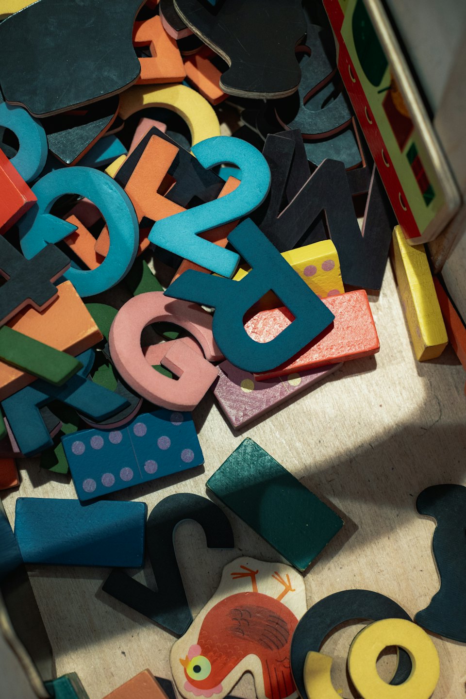 Kolorowe drewniane zabawki edukacyjne przechowywane w drewnianym pudełku.