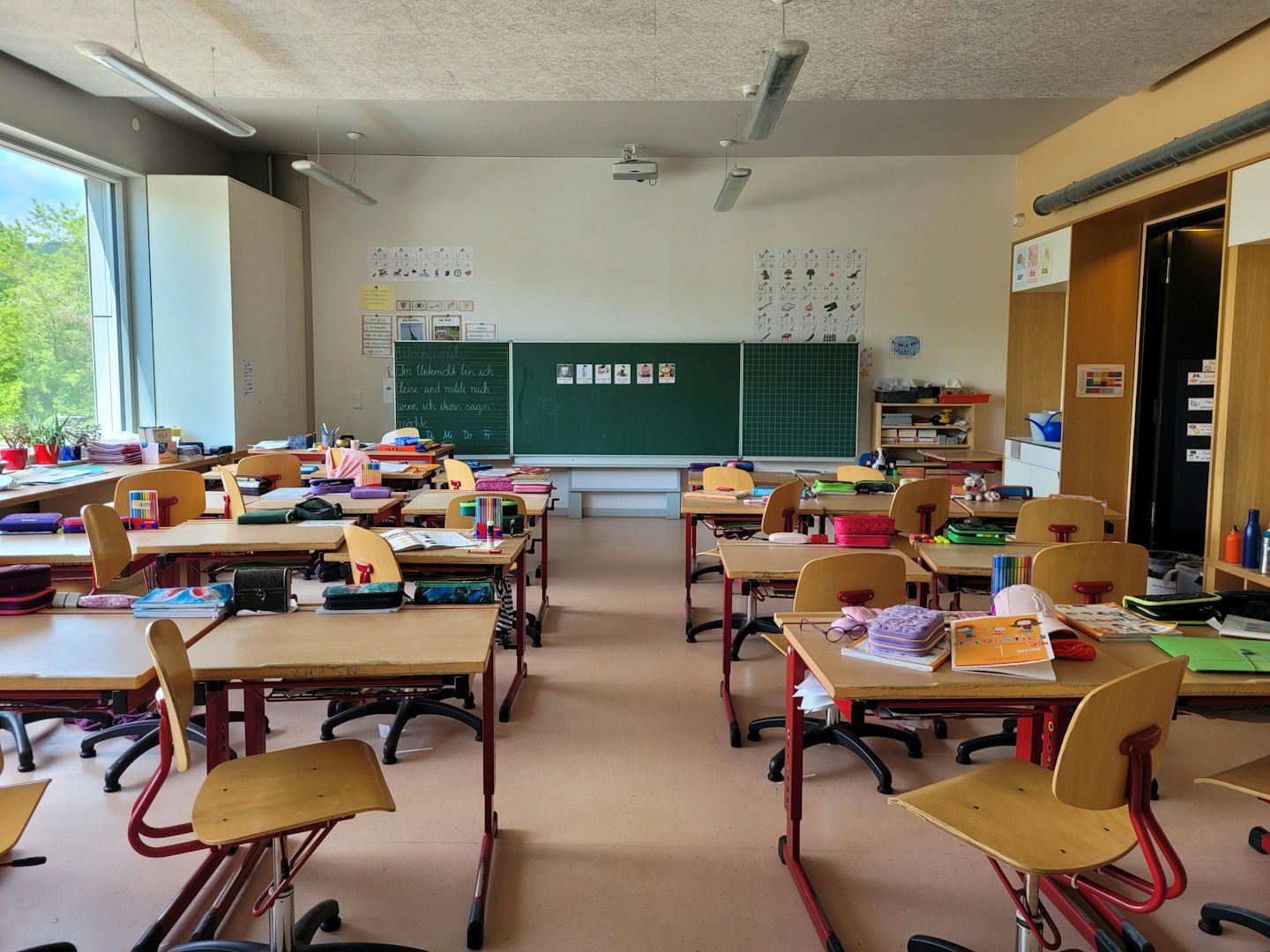 Pusta, nowoczesna sala lekcyjna z rzędami ławek i tablicą.
