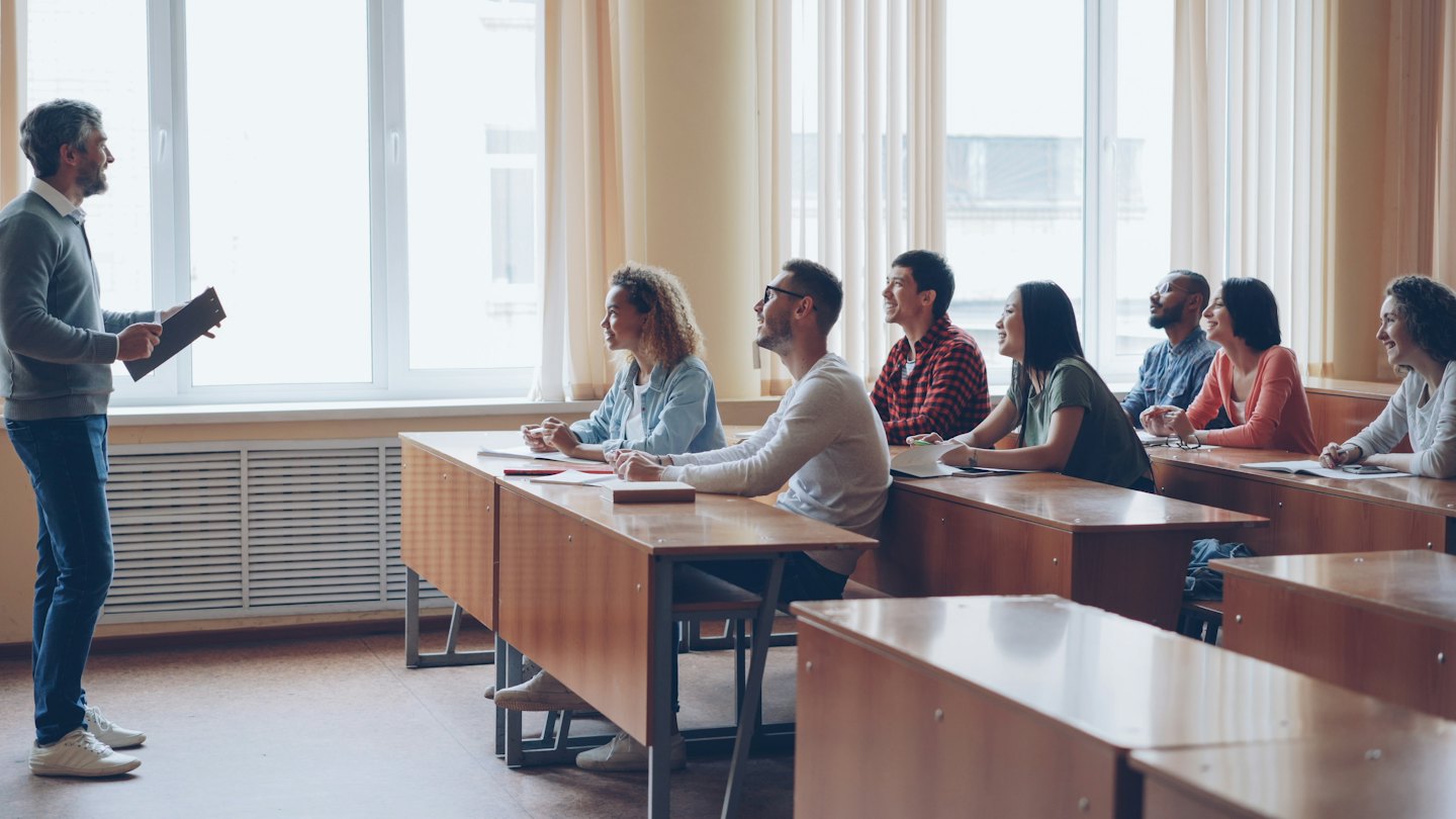 Nauczyciel z tablicą wykłada przed uważnymi studentami w sali wykładowej.